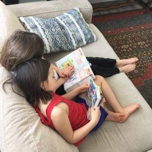 two children reading on a couch
