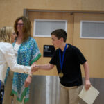 Board Chair Helen Gilbert congratulates one of the 2026 District Speech Contest top 3. Photo credit Adam Winn